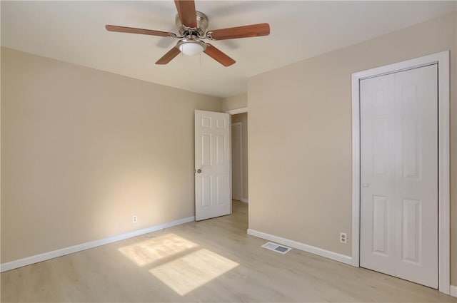 unfurnished bedroom with ceiling fan, light hardwood / wood-style flooring, and a closet