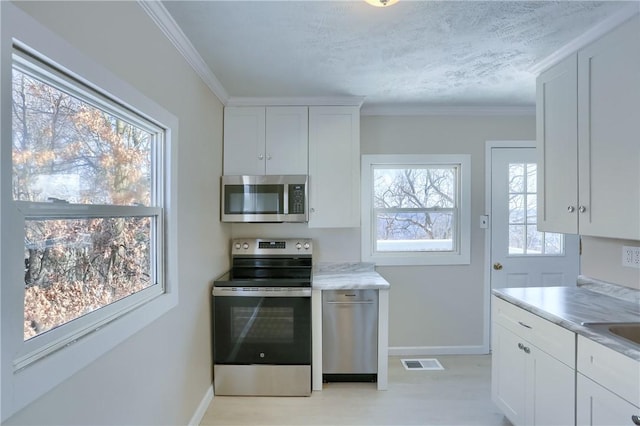 kitchen with white cabinets, stainless steel appliances, crown molding, and a textured ceiling