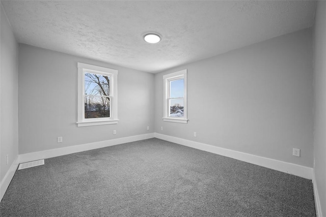 carpeted empty room featuring a textured ceiling