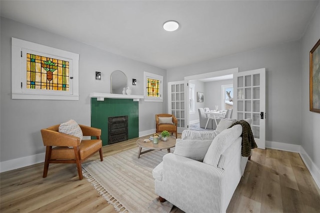 living room featuring light wood-type flooring, french doors, and a fireplace