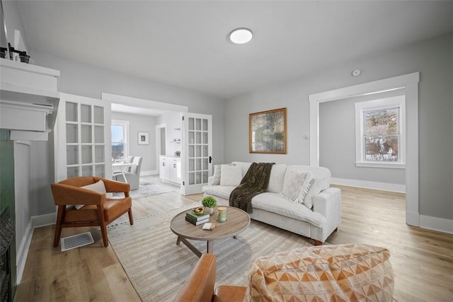 living room with light wood-type flooring, french doors, and a healthy amount of sunlight