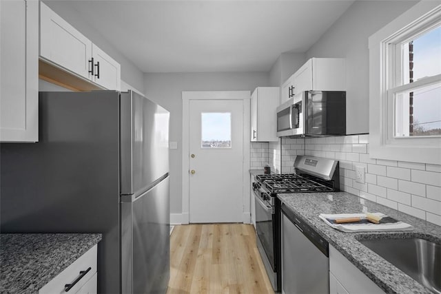 kitchen with white cabinets, dark stone countertops, and stainless steel appliances