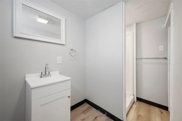 bathroom with hardwood / wood-style floors, a textured ceiling, walk in shower, and vanity