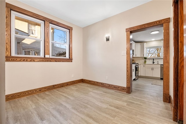 spare room with sink and light hardwood / wood-style floors