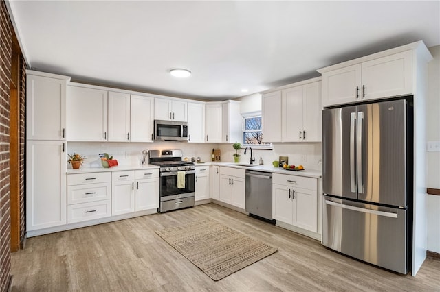 kitchen with backsplash, sink, white cabinetry, and appliances with stainless steel finishes