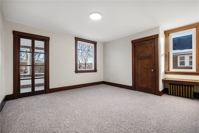 unfurnished bedroom featuring light carpet, multiple windows, and radiator