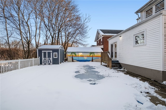 snowy yard featuring a storage unit