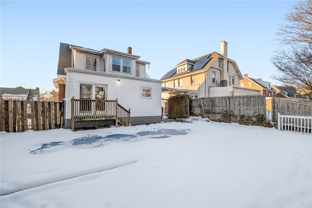 snow covered back of property with a wooden deck