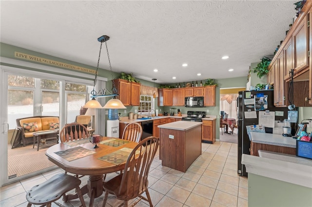 kitchen with decorative light fixtures, light tile patterned floors, black appliances, and a kitchen island