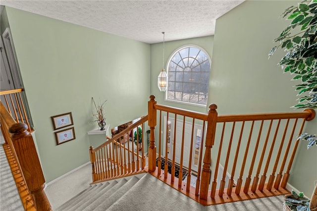 stairway featuring a textured ceiling and carpet flooring