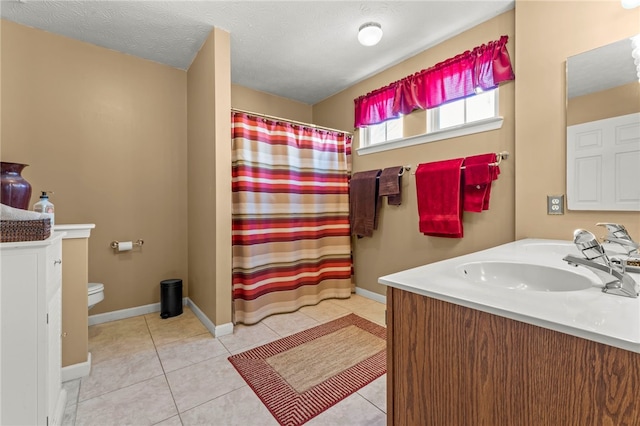 bathroom with a textured ceiling, tile patterned flooring, vanity, toilet, and walk in shower