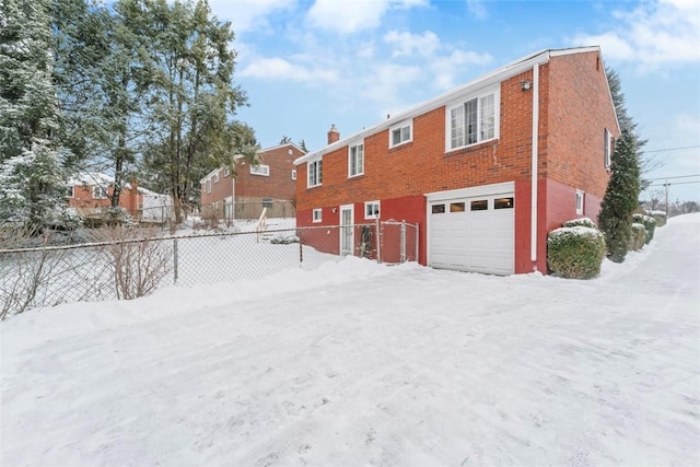 snow covered back of property with a garage