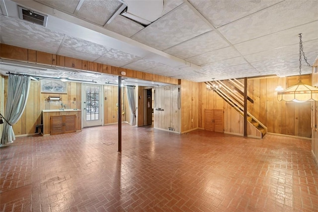 basement featuring wood walls and a drop ceiling