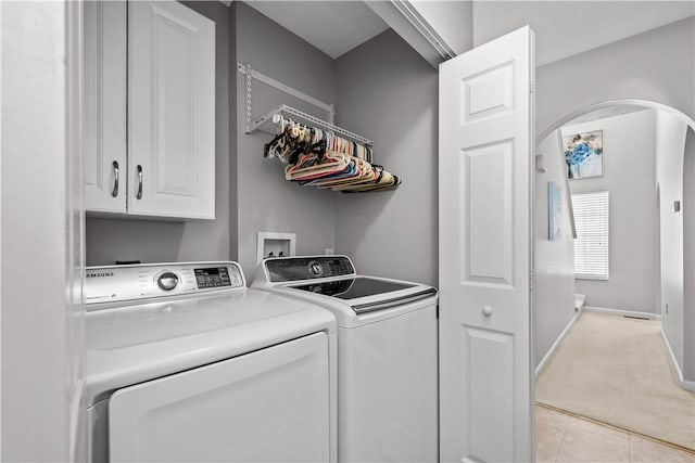 laundry area featuring washer and dryer, cabinets, and light tile patterned floors