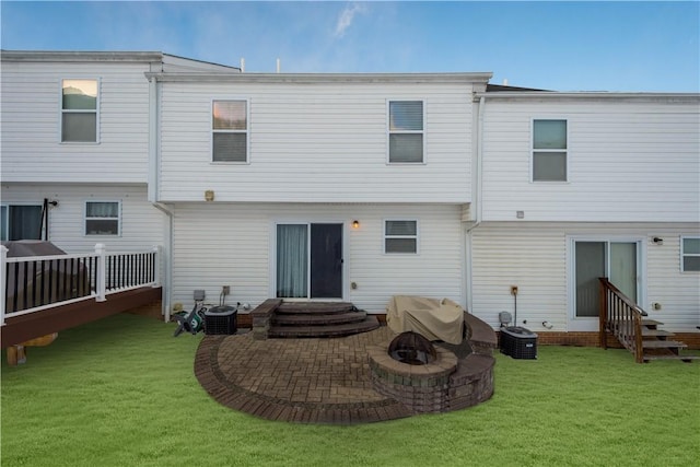 back of property with cooling unit, a patio, a lawn, and a fire pit