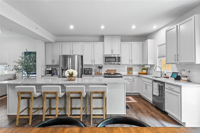 kitchen with white cabinets, a kitchen island, stainless steel appliances, sink, and a breakfast bar