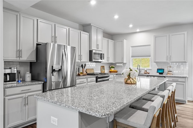 kitchen featuring light stone countertops, a center island, stainless steel appliances, and a breakfast bar area