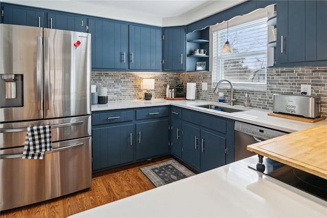 kitchen featuring sink, backsplash, appliances with stainless steel finishes, and blue cabinets