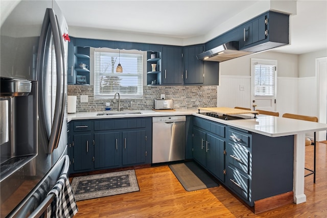 kitchen with kitchen peninsula, sink, blue cabinets, a breakfast bar area, and stainless steel appliances