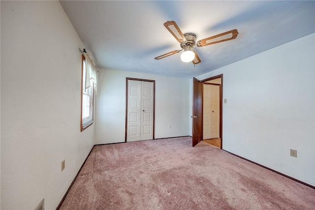 unfurnished bedroom featuring ceiling fan, light colored carpet, and a closet