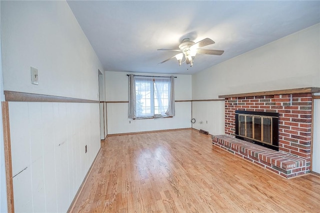 unfurnished living room with ceiling fan, light hardwood / wood-style flooring, and a brick fireplace