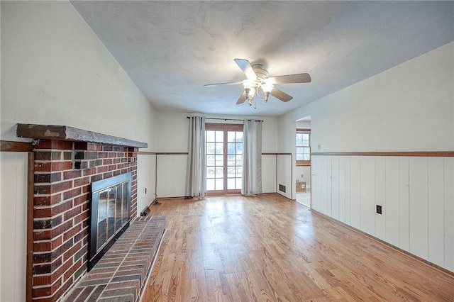 unfurnished living room featuring ceiling fan, light hardwood / wood-style flooring, and a fireplace