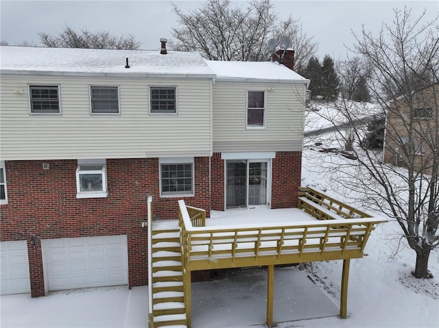 snow covered rear of property with a garage