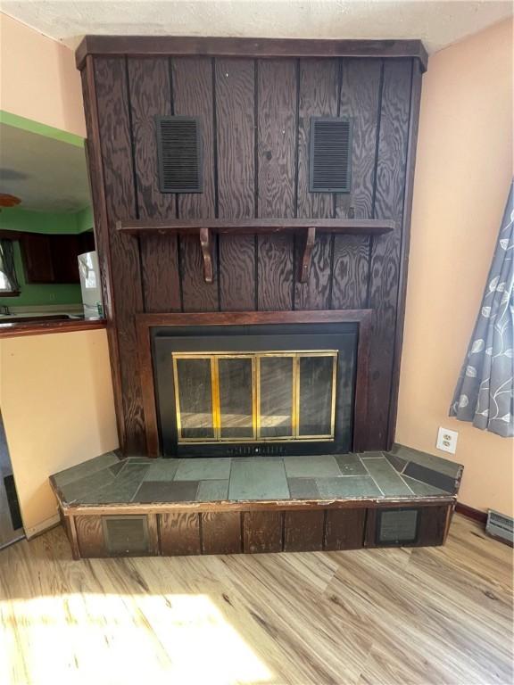 interior details with hardwood / wood-style flooring and a tiled fireplace