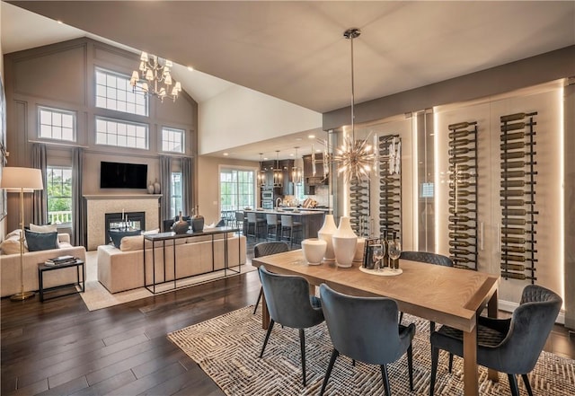 dining space with high vaulted ceiling, dark hardwood / wood-style flooring, a healthy amount of sunlight, and an inviting chandelier