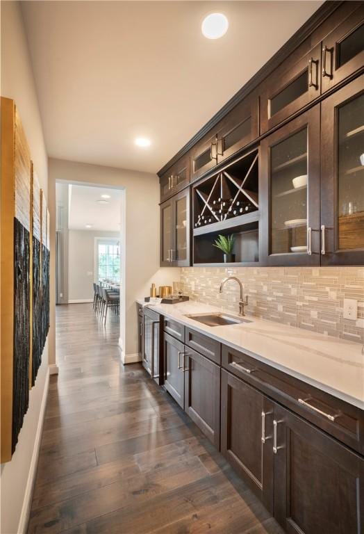 bar with sink, decorative backsplash, dark hardwood / wood-style floors, and dark brown cabinetry