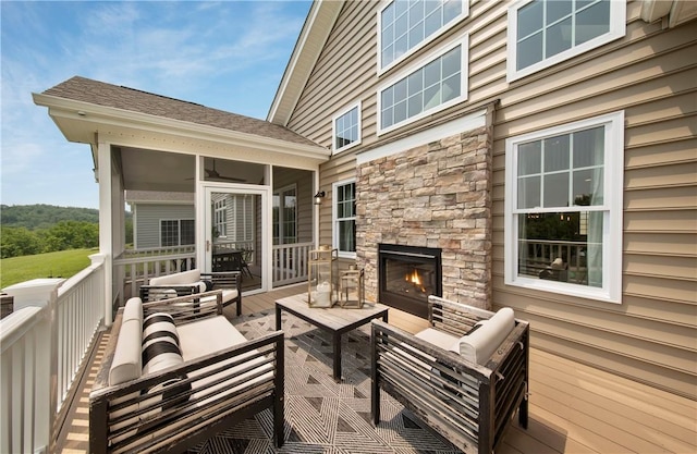 wooden deck featuring a sunroom and an outdoor living space with a fireplace