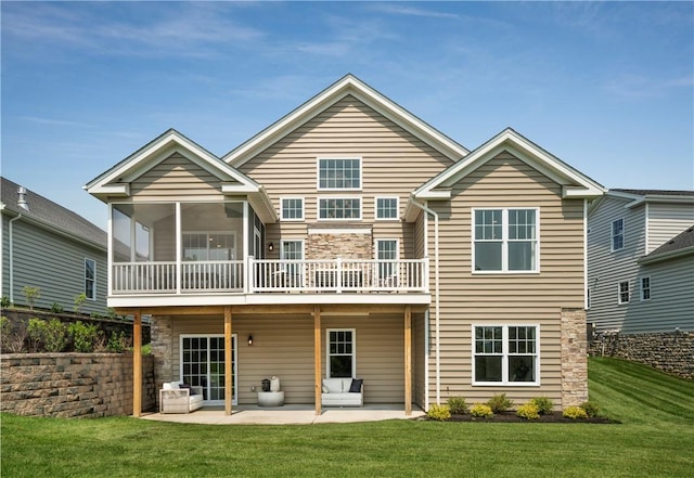 back of property with a sunroom, a patio area, and a lawn