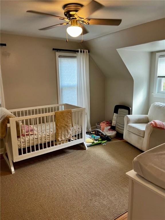 bedroom featuring ceiling fan, carpet, vaulted ceiling, and a crib