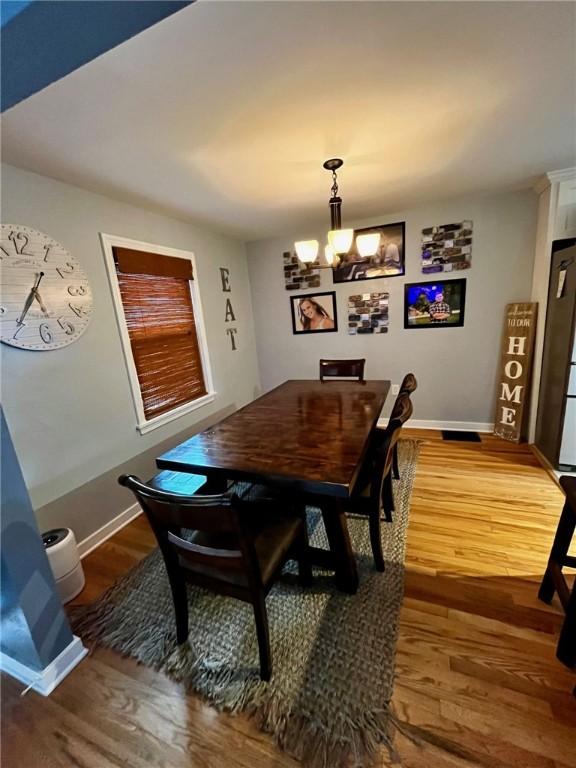 dining space with hardwood / wood-style floors and an inviting chandelier