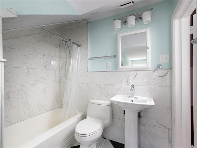 bathroom with toilet, shower / tub combo, and tile walls