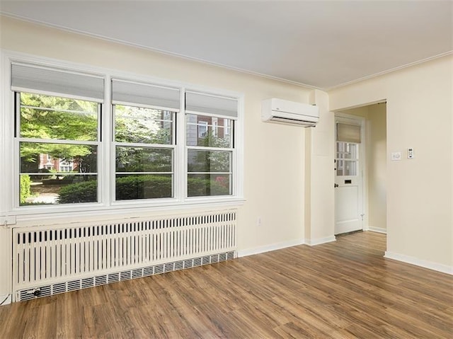 empty room with hardwood / wood-style flooring, radiator, and a wall mounted AC