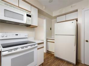 kitchen with white cabinets, white appliances, and dark wood-type flooring