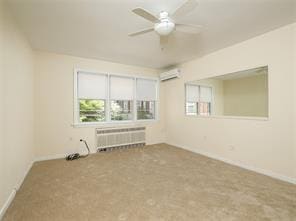 spare room featuring ceiling fan, radiator, and a wall unit AC