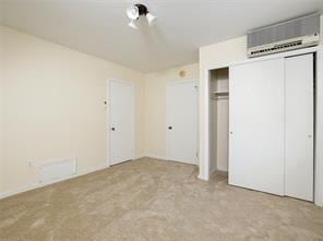 unfurnished bedroom featuring an AC wall unit, light colored carpet, and a closet