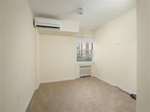 carpeted empty room featuring a wall mounted air conditioner