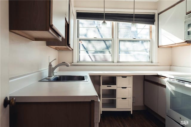 kitchen featuring sink, decorative light fixtures, white appliances, and dark wood-type flooring