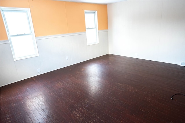 empty room featuring a healthy amount of sunlight and dark hardwood / wood-style floors