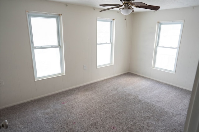 carpeted spare room featuring ceiling fan and a wealth of natural light