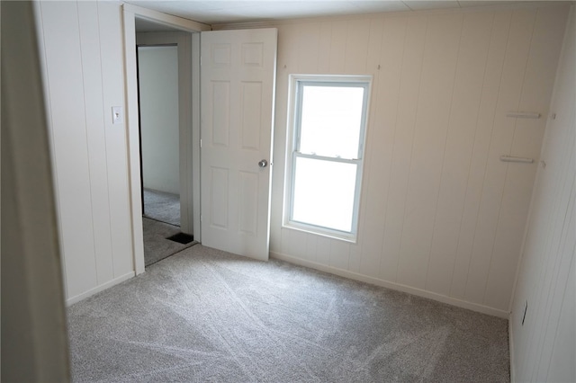 spare room featuring wood walls, a wealth of natural light, and carpet