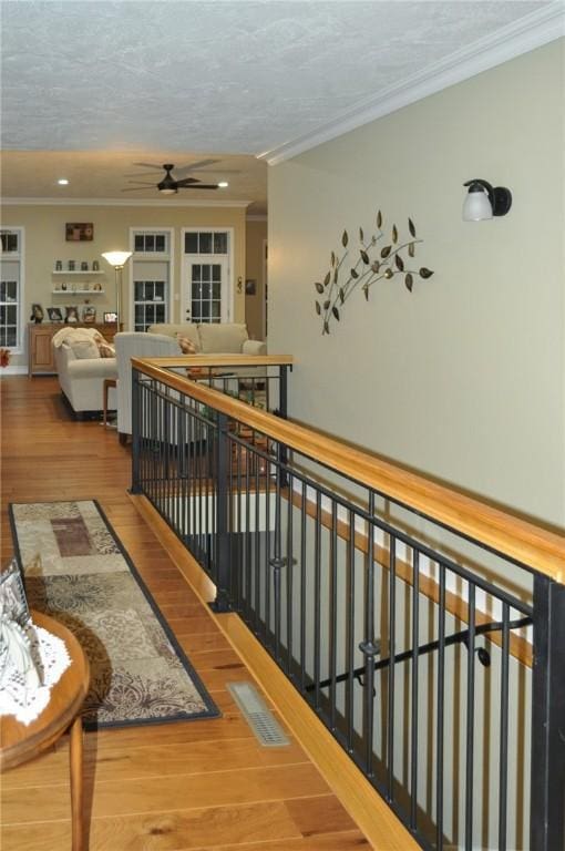 hallway with hardwood / wood-style flooring, a textured ceiling, and ornamental molding