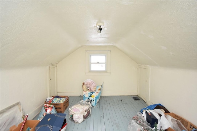 bonus room featuring lofted ceiling, light wood-type flooring, and a textured ceiling