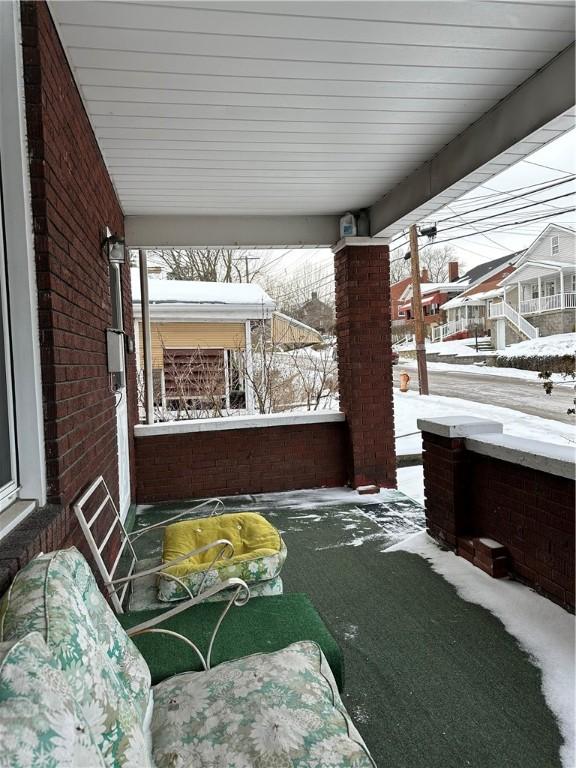 snow covered patio with a porch