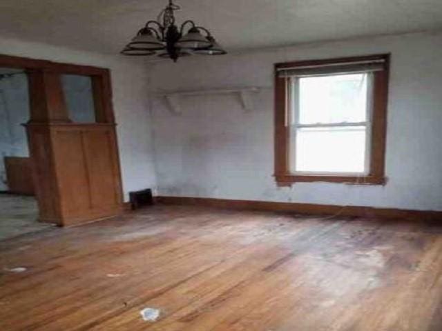 unfurnished dining area featuring wood-type flooring and a notable chandelier