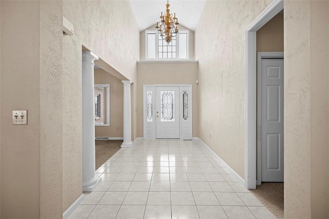 foyer with high vaulted ceiling, a chandelier, light tile patterned floors, and ornate columns