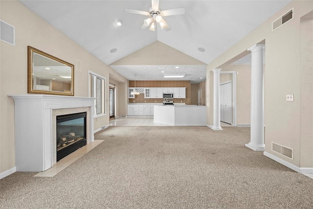 unfurnished living room featuring decorative columns, light carpet, ceiling fan, and vaulted ceiling